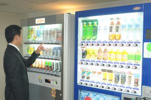 un uomo in piedi di fronte a un distributore di bevande energetiche di Nawa Plaza Hotel a Tokai