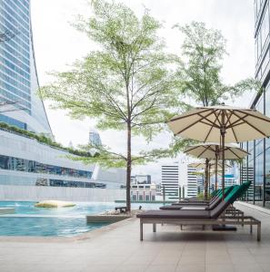 曼谷的住宿－Sivatel Bangkok Hotel，游泳池旁带遮阳伞的长凳