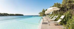 a row of chairs and umbrellas next to a swimming pool at Crvena Luka Resort in Biograd na Moru