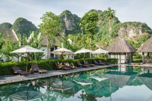 a pool at a resort with chairs and umbrellas at Aravinda Resort Ninh Binh in Ninh Binh