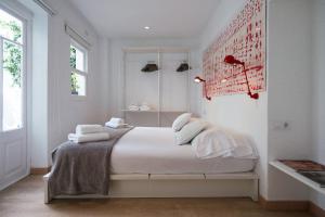 a white bedroom with a bed with towels on it at Cheap & Chic Hotel in Ciutadella