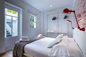 a bedroom with a white bed with a red lamp at Cheap & Chic Hotel in Ciutadella