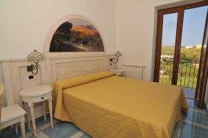 a bedroom with a yellow bed and a balcony at Hotel Isolabella in Ventotene