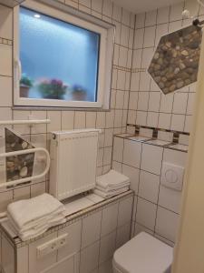 een wit betegelde badkamer met een toilet en een raam bij FeWo Marussia in Rust +23 foto's