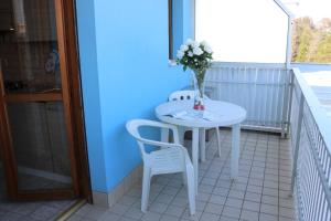 einen weißen Tisch mit 2 Stühlen und eine Vase mit Blumen auf dem Balkon in der Unterkunft Appartamenti Valbella in Bibione