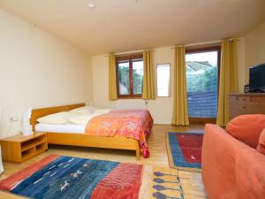 a bedroom with a bed and a couch and windows at Pension Popotnik in Villach