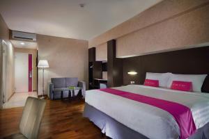 a hotel room with a large bed with red pillows at favehotel Graha Agung Surabaya in Surabaya