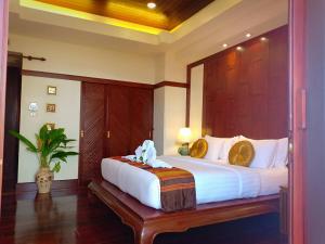 una camera con un grande letto con testiera in legno di Baan Thai Lanta Resort a Ko Lanta