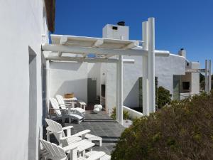 a group of white chairs and tables on a patio at Salt Water House in Paternoster