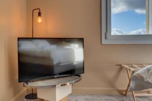 a flat screen tv sitting on a stand in a living room at Hôtel Une Chambre en Ville in Toulouse