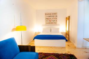 ein Schlafzimmer mit einem Bett und einem blauen Stuhl in der Unterkunft Funicular Inn Apartments in Tbilisi City
