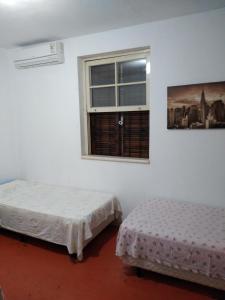 Duas camas num quarto com uma janela em Chacara Samambaia em Piracicaba