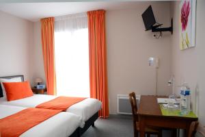 a bedroom with a bed and a desk and a window at Hôtel Restaurant La Paix La Robe et le Palais in Forges-les-Eaux