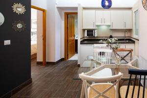 a kitchen and living room with a glass table and chairs at Apartamento Mágico Carretería in Málaga