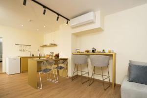 a kitchen with a counter and chairs in a room at SUITES@SYNGROU-FIX in Athens