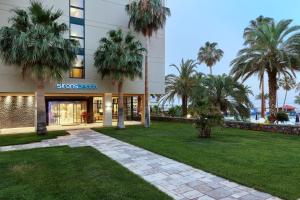 a building with palm trees in front of it at Sirens Beach & Village in Malia