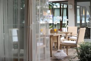 a dining table and chairs on a porch with glass doors at Apartamentai Tylios pušys in Palanga