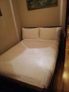 een bed met witte lakens en kussens in een kamer bij Mullaghbeag Lodge in Navan