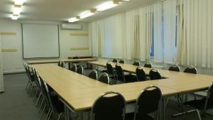 une salle de conférence avec des tables et des chaises et un tableau blanc dans l'établissement Hotel Astra, à Tuchlovice