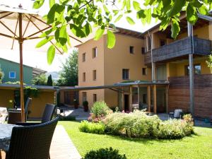 ein Haus mit einem Garten mit Stühlen und einem Sonnenschirm in der Unterkunft Pension Popotnik in Villach