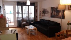 sala de estar con sofá negro y mesa en Apartamentos el Camino, en Villafranca del Bierzo
