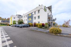 een gebouw met auto's geparkeerd op een parkeerplaats bij B&B HOTEL Beauvais in Beauvais