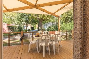 une terrasse en bois avec une table et des chaises. dans l'établissement Camping Le Méditerranée Argelès - Domaine piétonnier, à Argelès-sur-Mer
