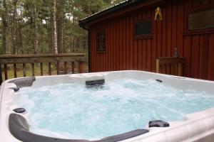 a hot tub in front of a cabin at Lagganlia Lodges and Camping Pods in Kincraig