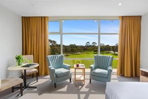 a hotel room with two chairs and a bed and a large window at Parkside Motel Geelong in Geelong