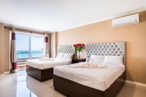 two beds in a bedroom with a view of the ocean at EM Royalle Hotel & Beach Resort in San Juan