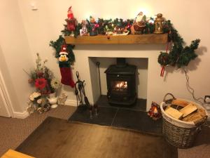 a living room with a fireplace with christmas decorations at PondeROSEa Cottage Free Gated Parking M1 & City location, wood stove in Lisburn