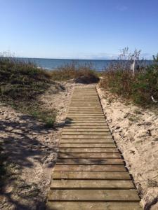 a wooden path leading to the ocean on a beach at D&A Baltic Beach Villa in Jūrmalciems