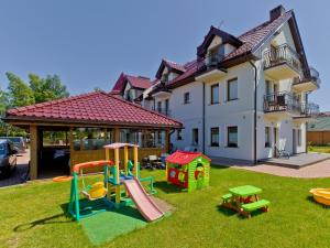 a yard with playground equipment in front of a house at Willa Złota Róża in Sarbinowo