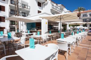 an outdoor patio with white tables and umbrellas at Globales Tamaimo Tropical in Puerto de Santiago
