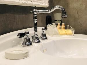lavabo blanco con grifo cromado y cosméticos en Saint B Boutique Hotel STB en Roma