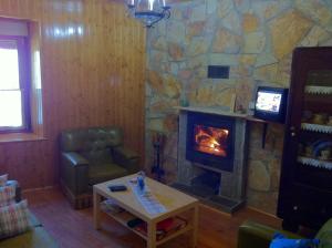 sala de estar con chimenea de piedra y mesa en La Casa del Maestro, en Rabanal