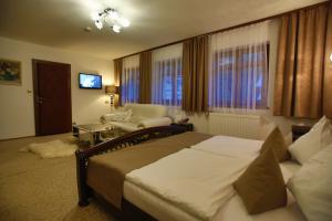 a bedroom with a bed and a chair and a television at Hotel Jelinek in Špindlerův Mlýn