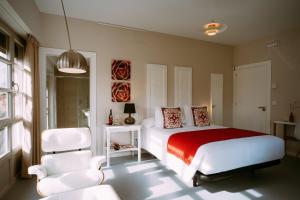 a bedroom with a bed and two white chairs at el gran sueño Boutique Hotel & Apartamentos - Adults Only in Pintueles