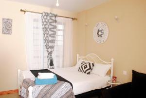 a small bedroom with a white bed and a window at WEST SUITES SHERRY HOMES in Nairobi