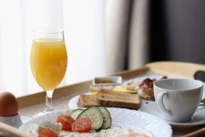 a table with a plate of food and a glass of orange juice at Guest House Panorama Aqualux in Novi Sad