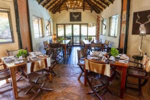 uma sala de jantar com mesas e cadeiras de madeira em Ijaba Lodge at Buschfeld Park em Outjo