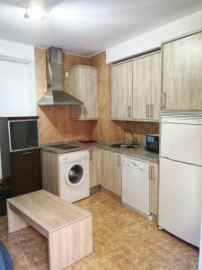 eine Küche mit Holzschränken, einer Waschmaschine und einem Trockner in der Unterkunft Apartamento Coco 567 in Avila