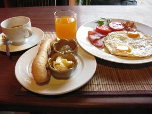 a table with two plates of breakfast food and a cup of orange juice at Cat Ba Bay Vision Hotel in Cat Ba