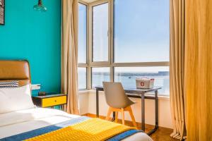 a bedroom with a bed and a desk and a window at Qingdao Huangdao·Qingdao Silver Beach· in Qingdao
