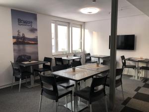 a dining room with tables and chairs and a tv at Brygga Gjestehus in Harstad