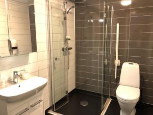 a bathroom with a shower and a toilet and a sink at Brygga Gjestehus in Harstad +12 photos
