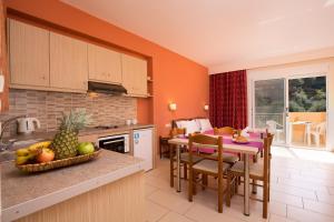 a kitchen and dining room with a table with fruit on the counter at Odysseus Apartments By Hotelius in Agios Gordios