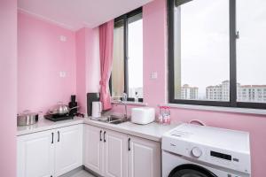 eine rosa Küche mit einer Spüle und einer Waschmaschine in der Unterkunft Luoyang Luolong·Baolong City Square in Luoyang