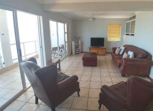 a living room with a couch and chairs and a tv at Crystal Sea House in St Helena Bay