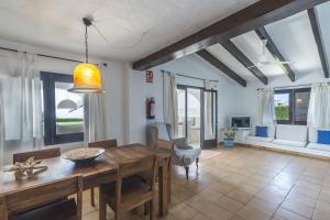 a dining room with a wooden table and some windows at Villa Bini Andu in Binibeca